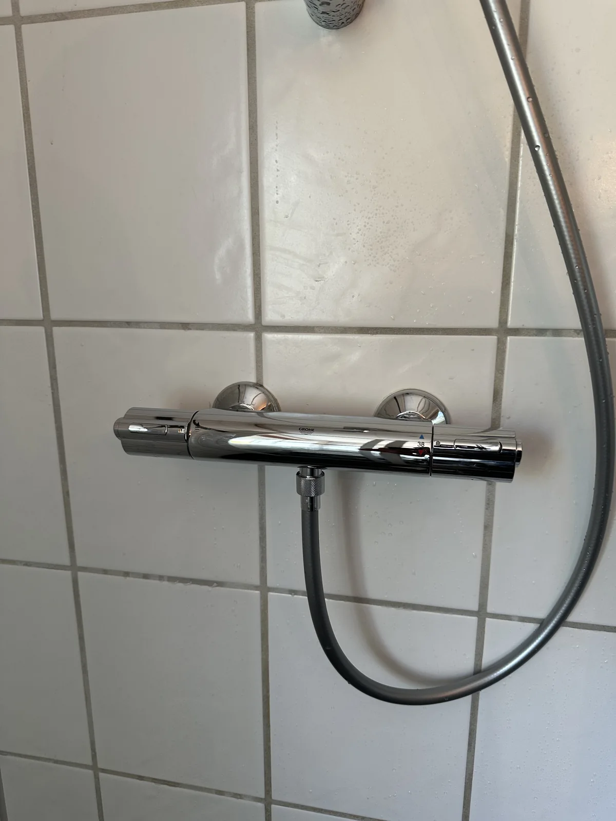 Nyt brusearmatur med bruseslange på badeværelsets flisevæg